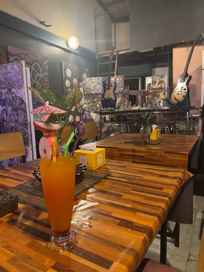Guitars on stands and paintings at the back of the room, a table in front