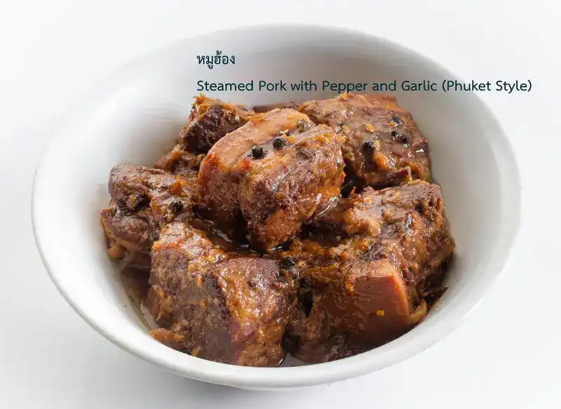 Dark braised pork belly with whole peppercorns in a white bowl