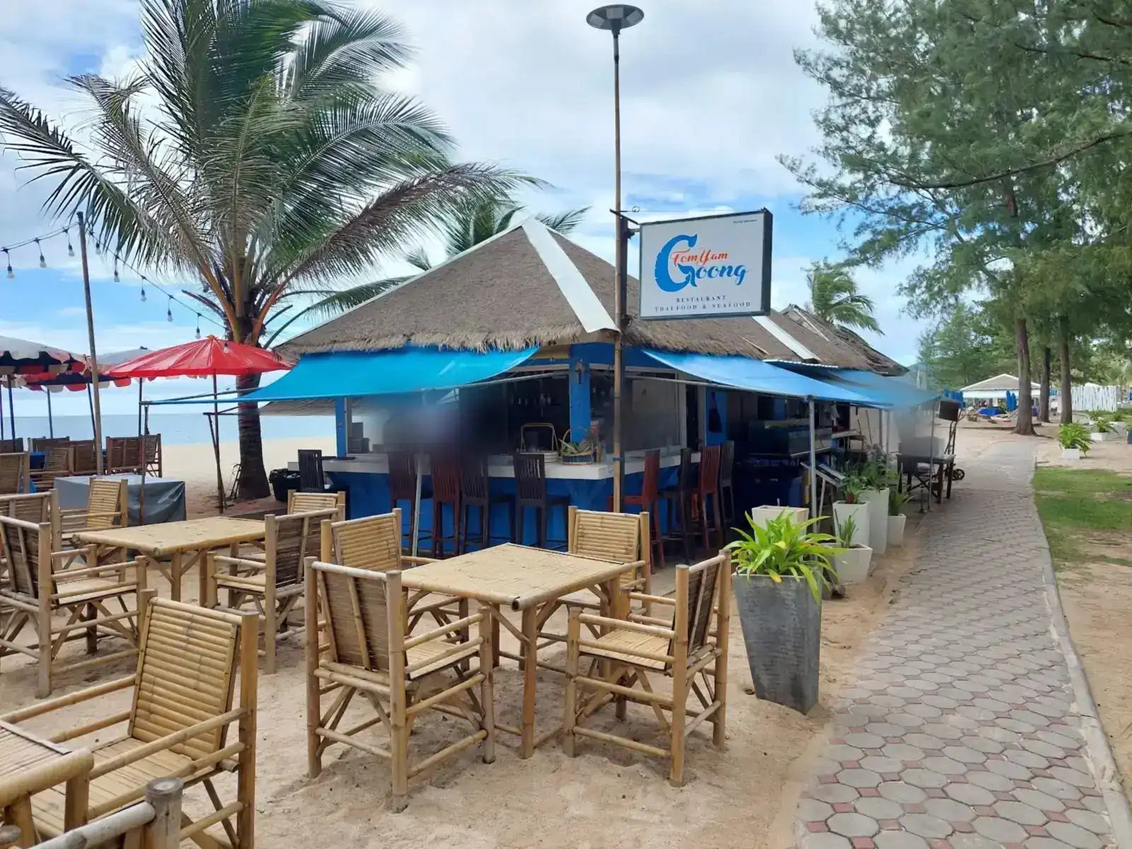 Tom Yam Goong's thatched hut and bamboo tables on the sand at Bang Tao Beach
