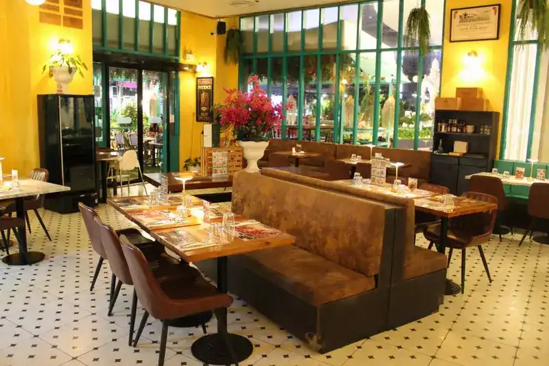 Brown banquettes and wooden tables on the tiled floor, with pink bougainvillea