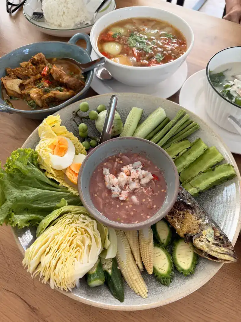 A table at Baan Ma: a nam chup platter with vegetables and fried fish, a curry and a soup
