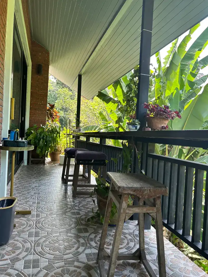 The long balcony, with patterned floor tiles, stools along the rail and potted plants