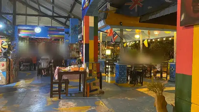 The restaurant in the evening: colour-blocked pillars, a blue painted floor and string lights over the tables at the back