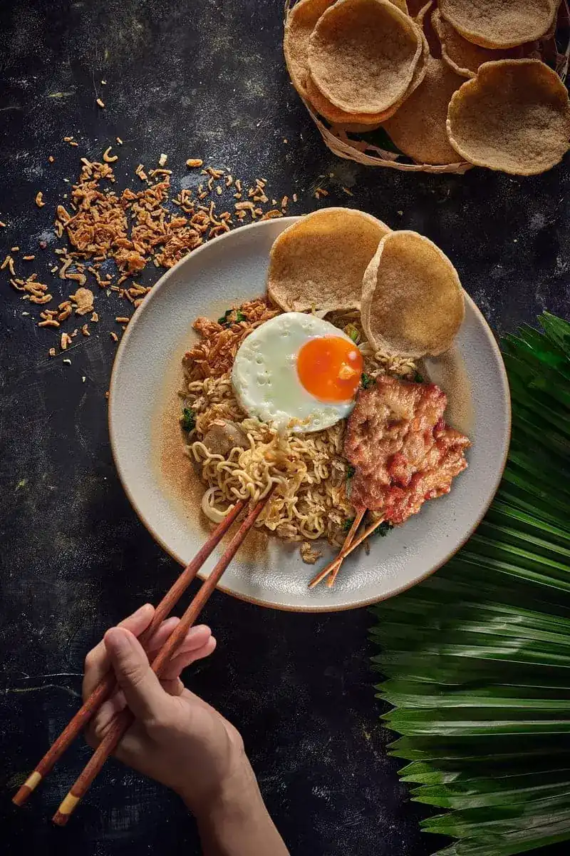 Mee Goreng fried noodles with a fried egg, crackers and grilled pork