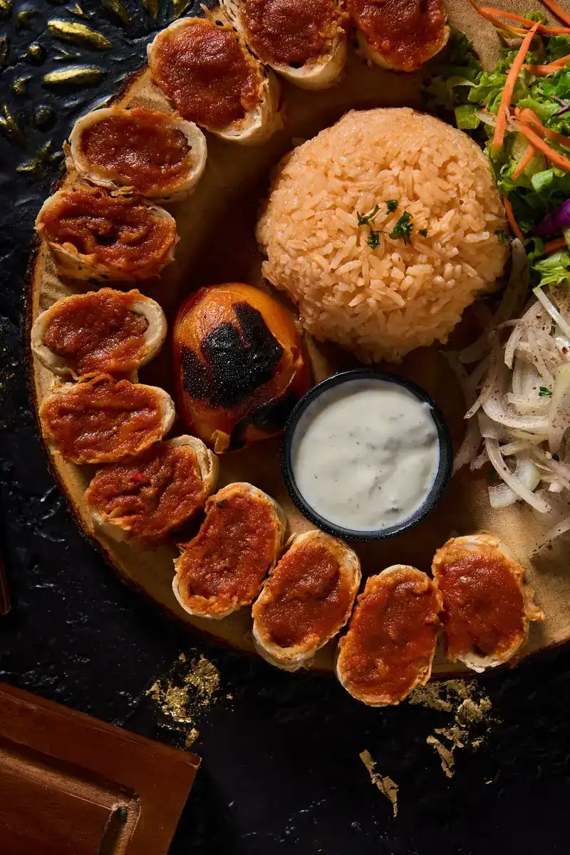 A round platter from the grill with a yoghurt dip, rice and onions