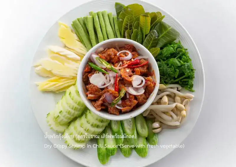 A bowl of crispy shrimp chilli relish ringed with fresh vegetables