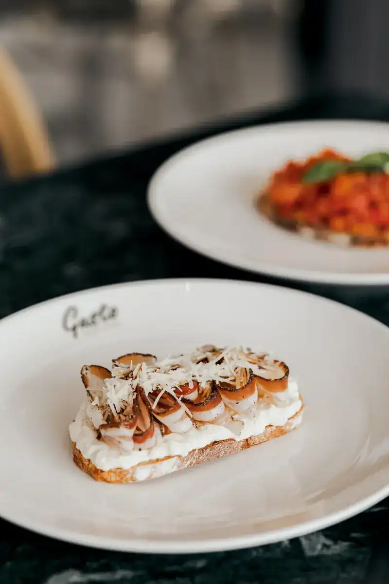 Toasted bread with soft cheese and cured meat on a Gusto plate