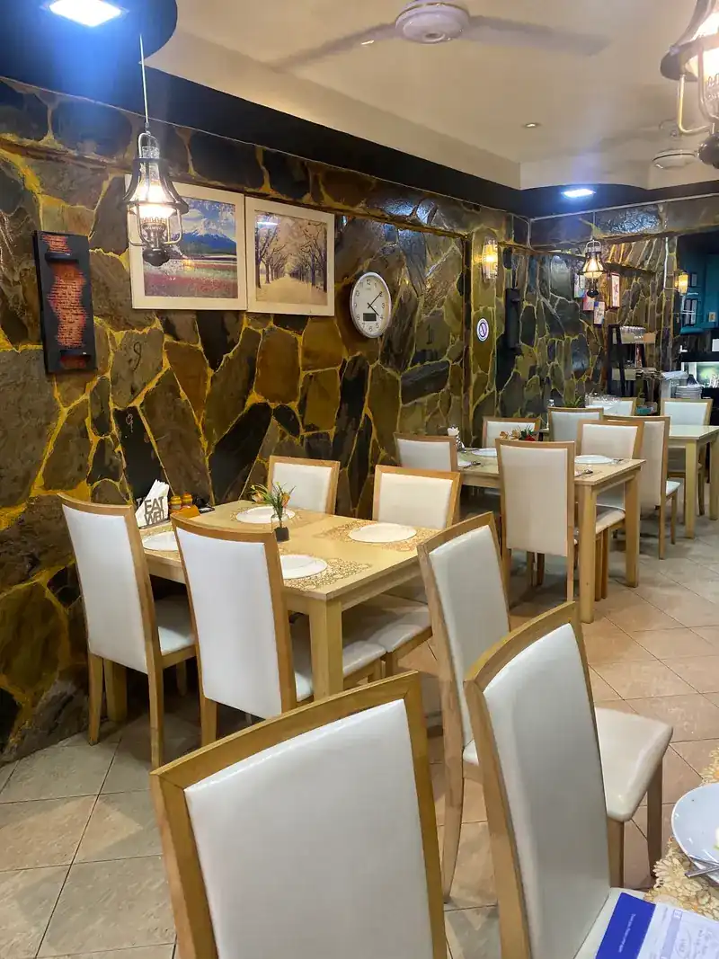 The dining room: stone walls, lanterns and rows of tables with white chairs