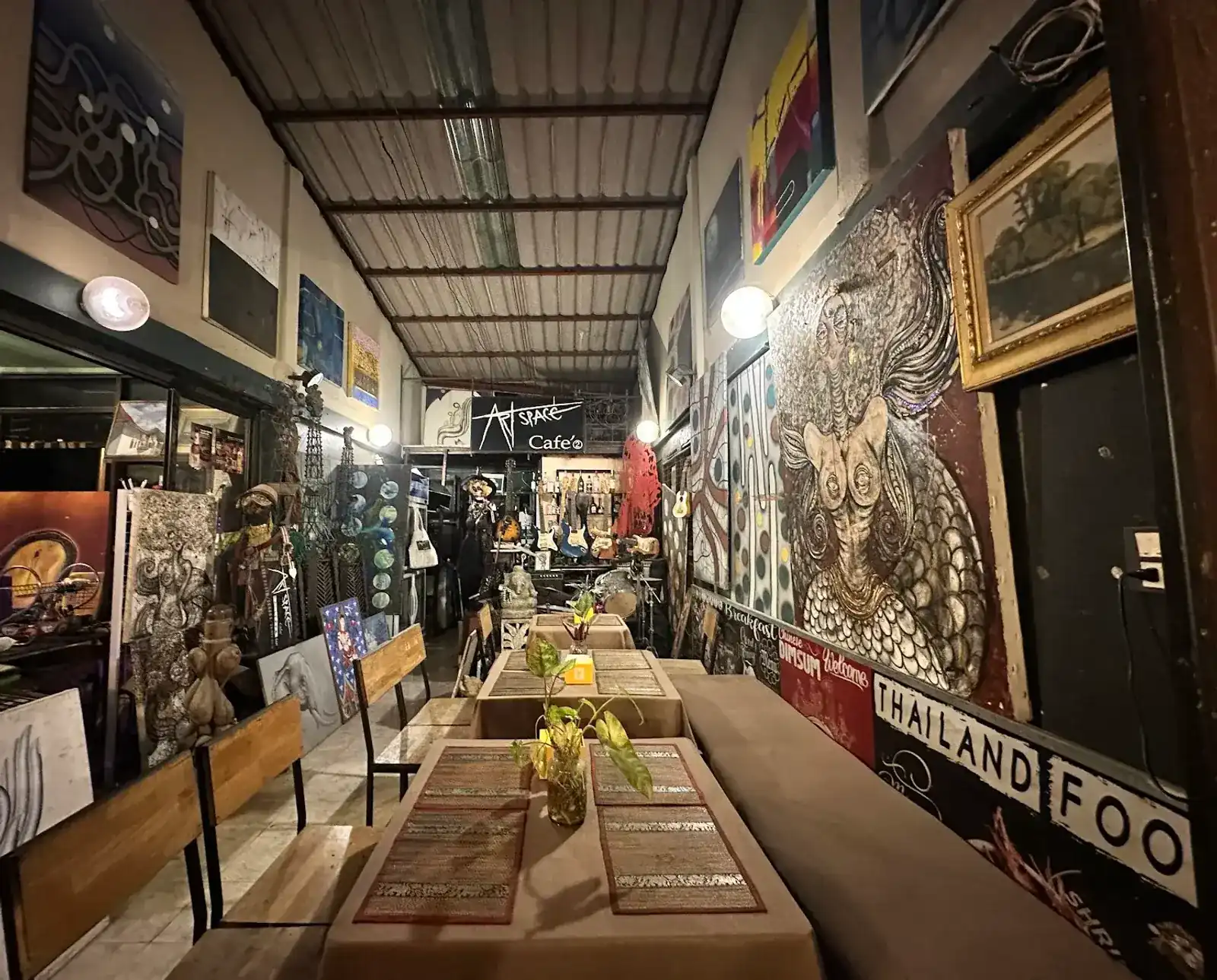 The long dining room at Art Space Cafe, walls hung with paintings, guitars and a drum kit at the far end