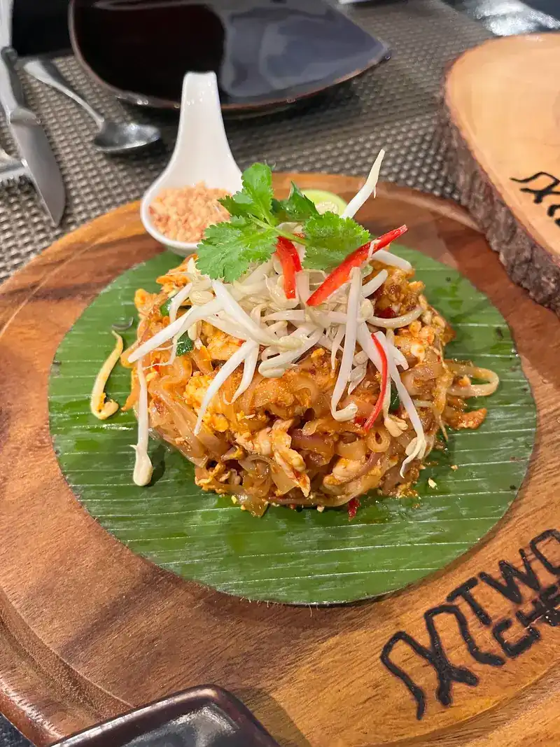Pad Thai on a banana leaf, topped with bean sprouts, chili and coriander