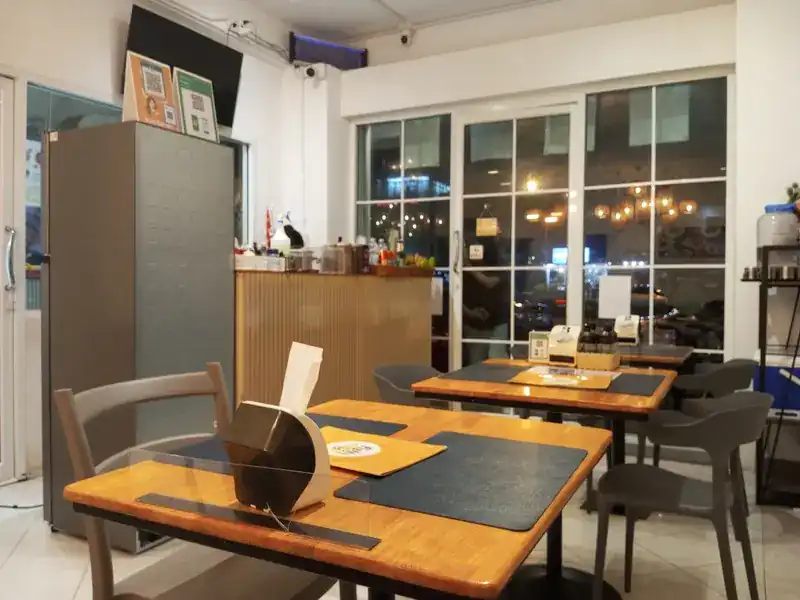 The dining room: wooden tables, dark chairs and glass doors to the street