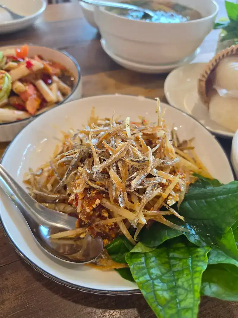Close-up of the salad heaped with crisp little fried fish, fresh green leaves at its side