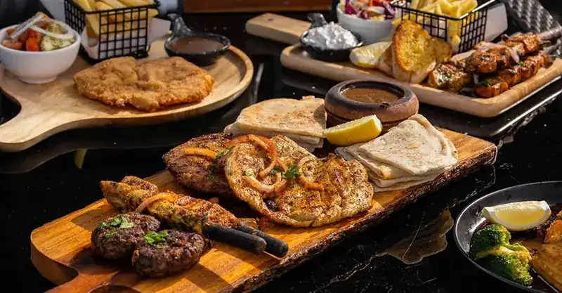 Grilled meats and pita bread on wooden boards, with fries and dips