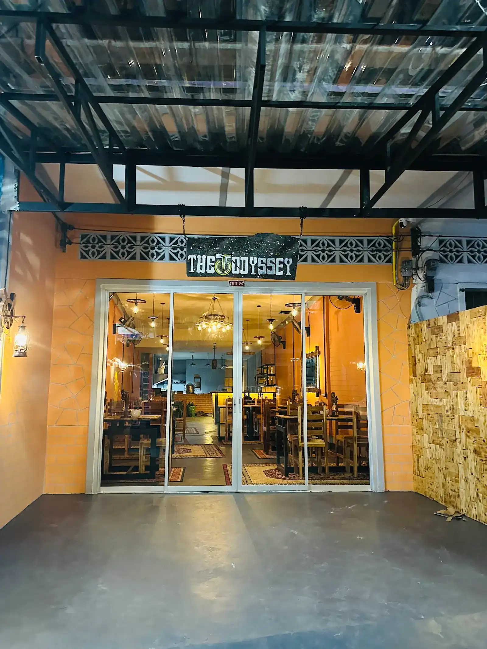 The Odyssey from the street: the hand-painted starry sign above the glass doors, wooden tables and lights inside