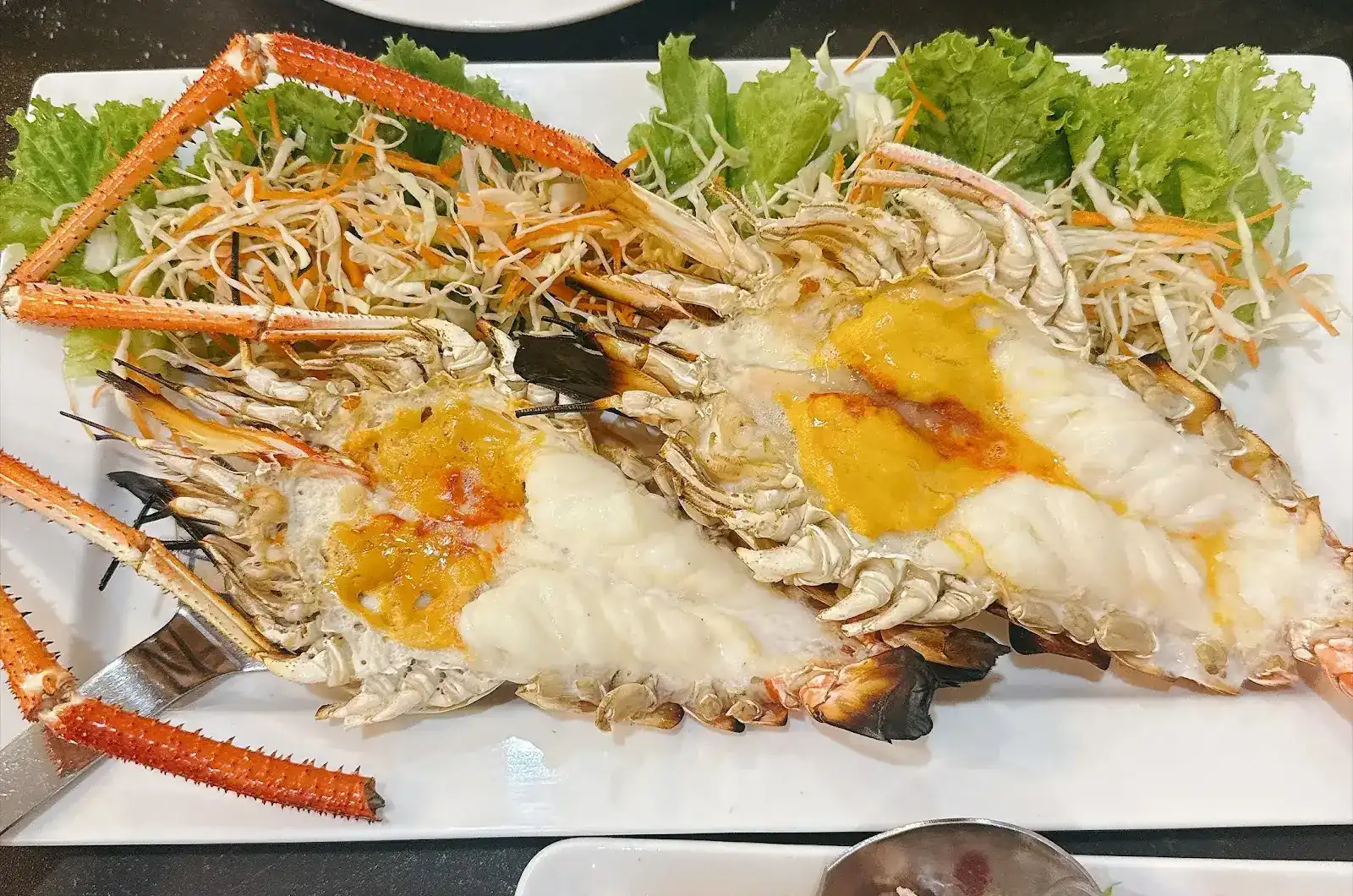 Two grilled giant river prawns, split open, on lettuce and shredded cabbage