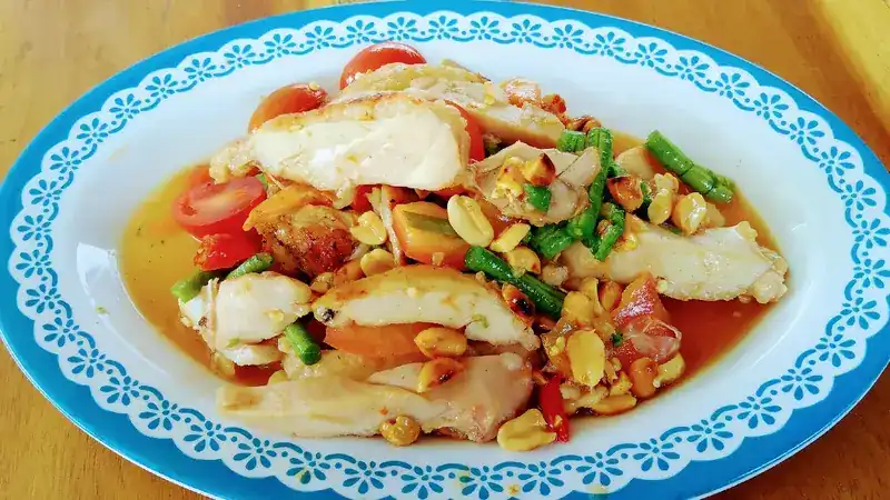 Papaya salad with peanuts, long beans and tomatoes on a lace-patterned plate