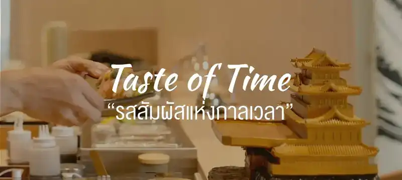 Hands plating at the counter beside a golden model of a Japanese castle, with the restaurant's line: Taste of Time, รสสัมผัสแห่งกาลเวลา