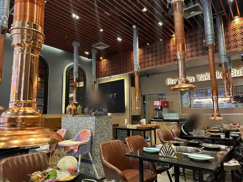The dining room: copper hoods over the grill tables, leather chairs and a copper lattice on the wall
