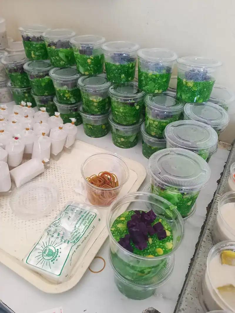Cups of green dessert, some topped with purple and yellow pieces