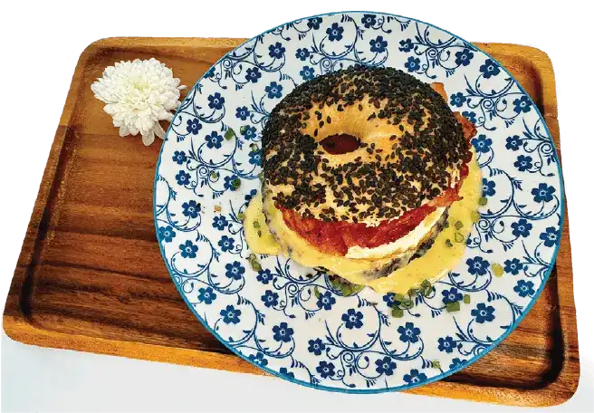 Bacon bagel with egg and cheese on a blue flowered plate