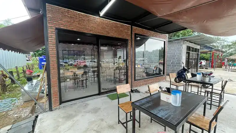 The shop: a glass-fronted room with red-brick walls and tables under an awning in front