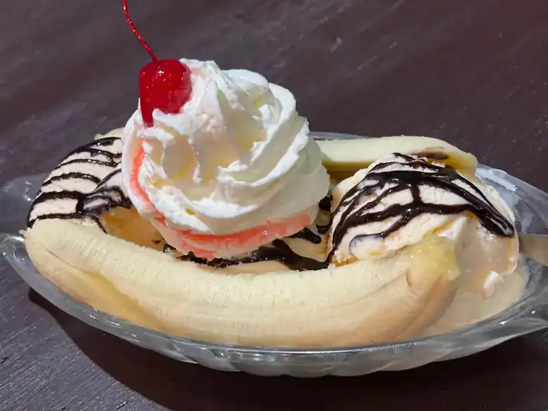 Banana split with whipped cream, chocolate sauce and a cherry
