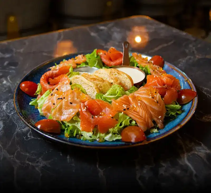 A salmon salad with toasted bread on a marble table by candlelight