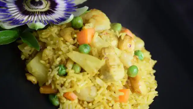 Yellow fried rice with pineapple, peas and carrot, a passion flower beside it