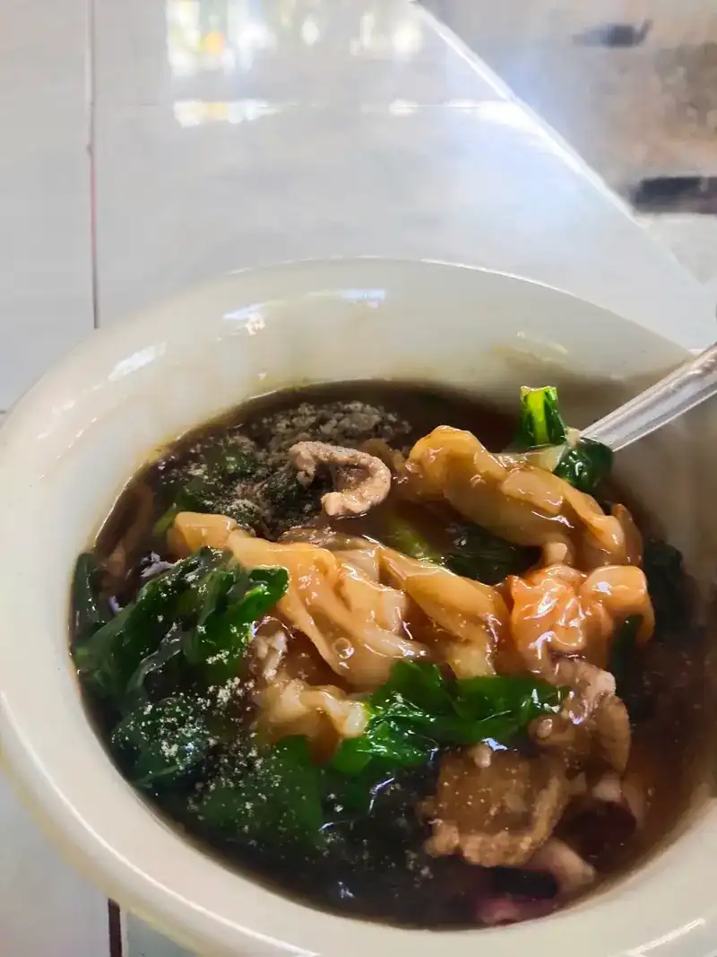 A guest's bowl of noodle soup with greens