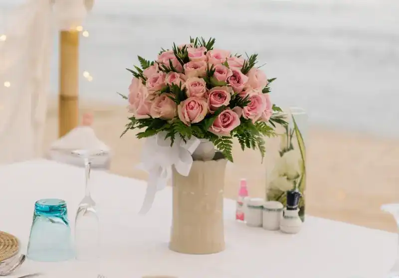 A bouquet of pink roses on a white-clothed table by the sea