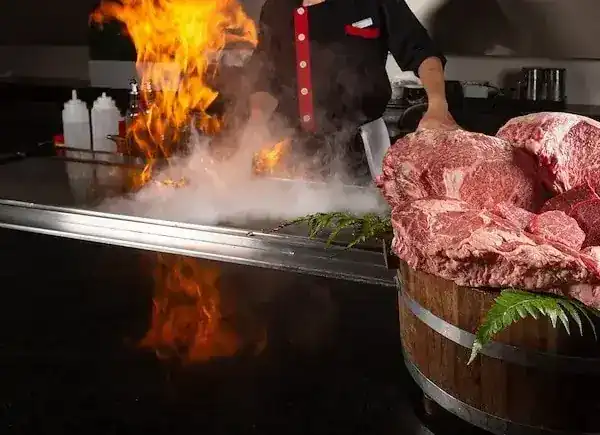 Wagyu beef beside the teppan, flames rising behind