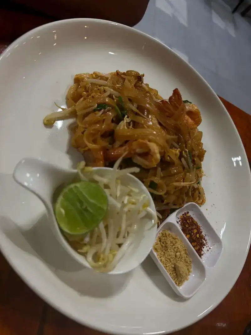Phad thai with prawns, a lime half, bean sprouts, chilli flakes and ground peanuts