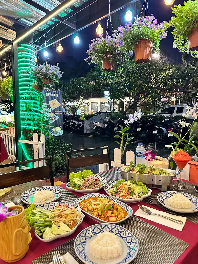 A Thai table on the terrace at night: salads, stir-fries and bowls of rice