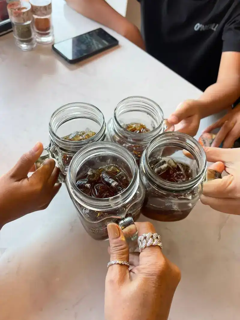 Four hands bringing jars of iced drinks together over the table