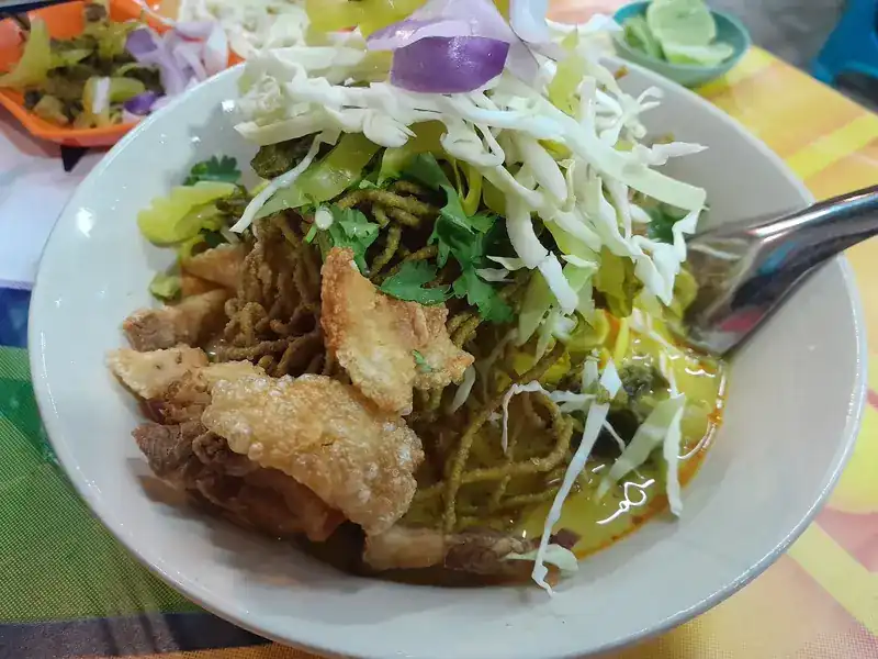 Khao soi with crispy pork, shredded cabbage and red onion