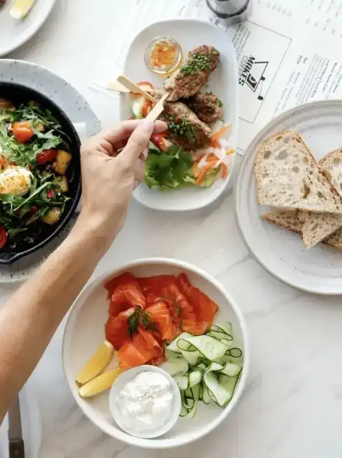 Smoked salmon, sourdough, skewers and a salad skillet on a marble table