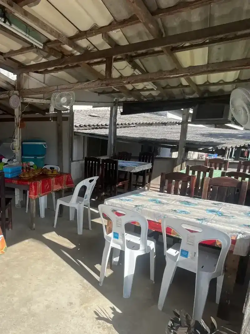 The open-air dining area: red and flowered tablecloths, white chairs and fans under the roof