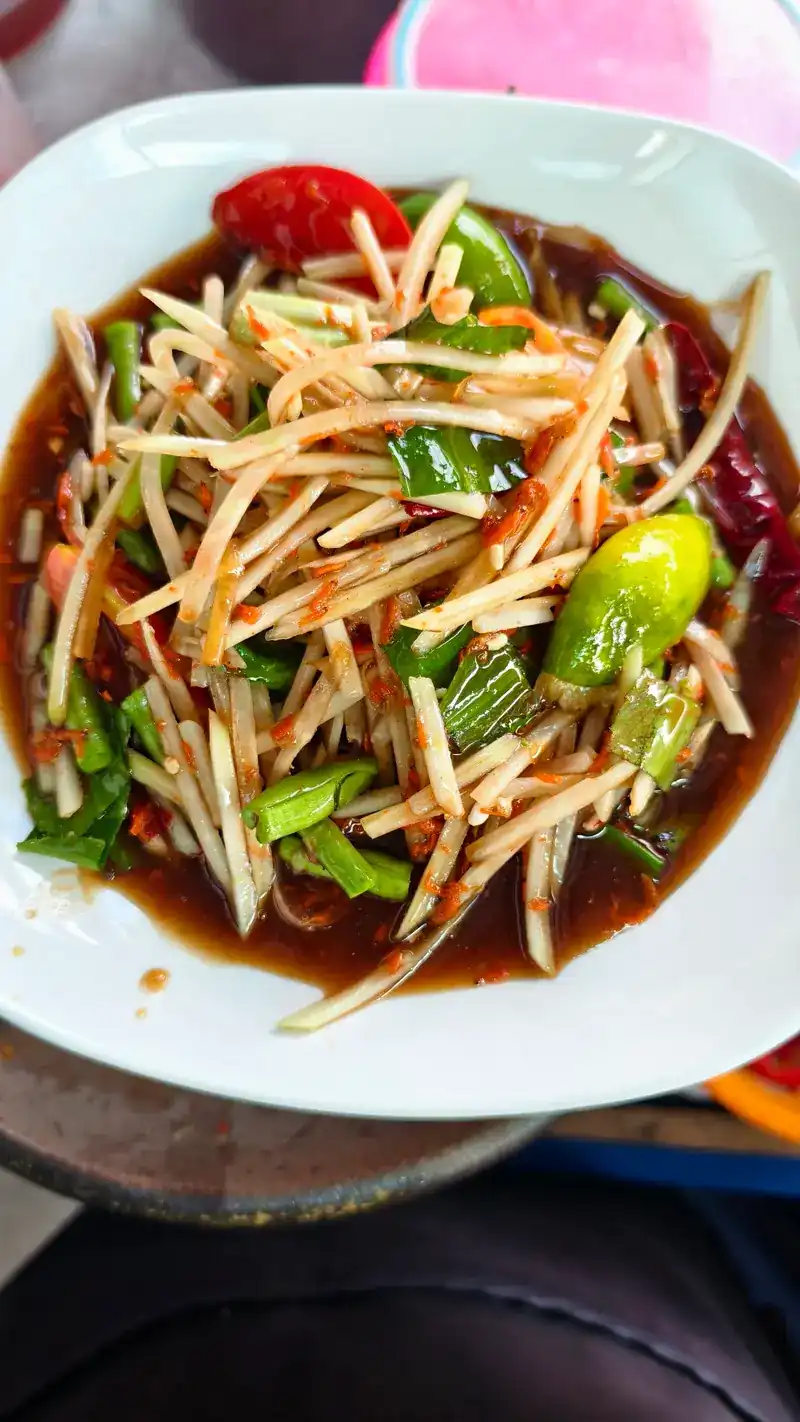 A plate of som tam with long beans and tomato