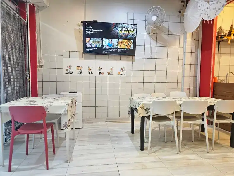 Dining room with white tiles, red pillars and tables laid with floral cloths / ห้องทานอาหาร ผนังกระเบื้องขาว เสาแดง โต๊ะปูผ้าลายดอก