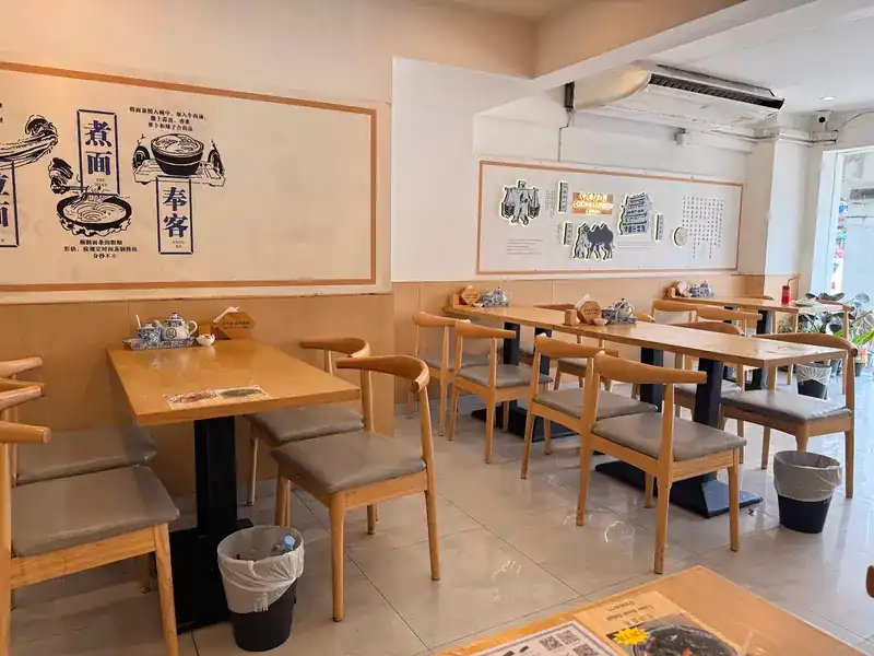 Dining room with wooden tables and a mural of noodle bowls on the wall