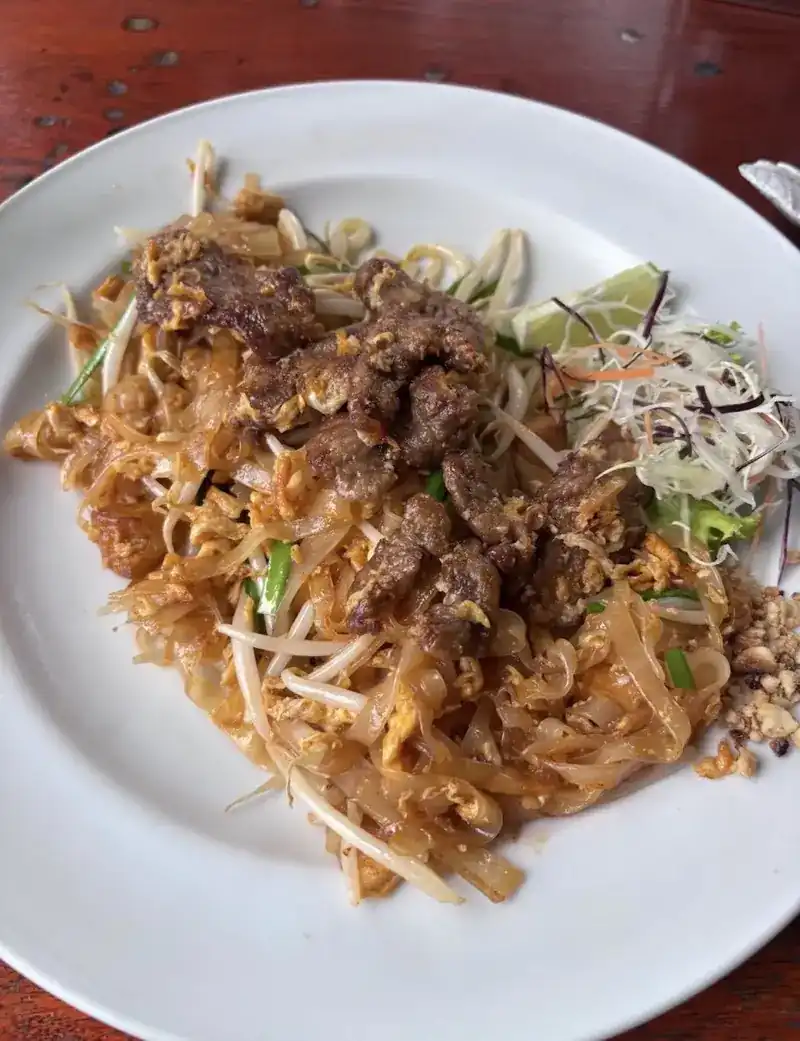 A plate of pad thai with lime and peanuts