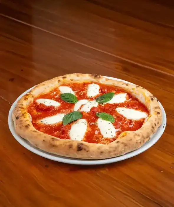 Pizza with tomato, mozzarella and basil leaves on a wooden table
