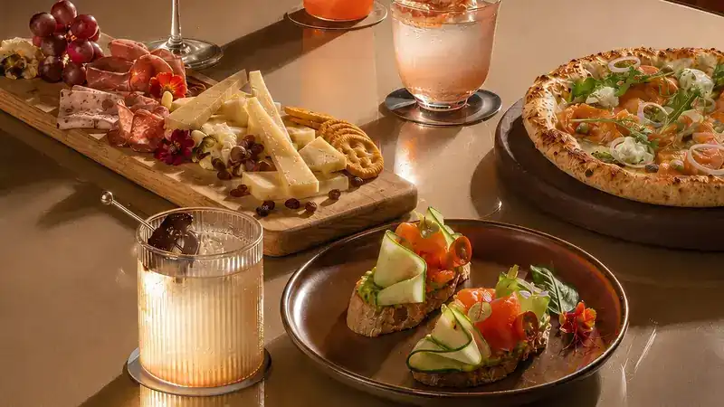 Bruschetta, a cheese and cold cut board and a pizza on a bronze table
