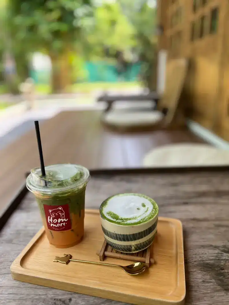 An iced matcha drink and a hot matcha latte on a wooden tray on the veranda
