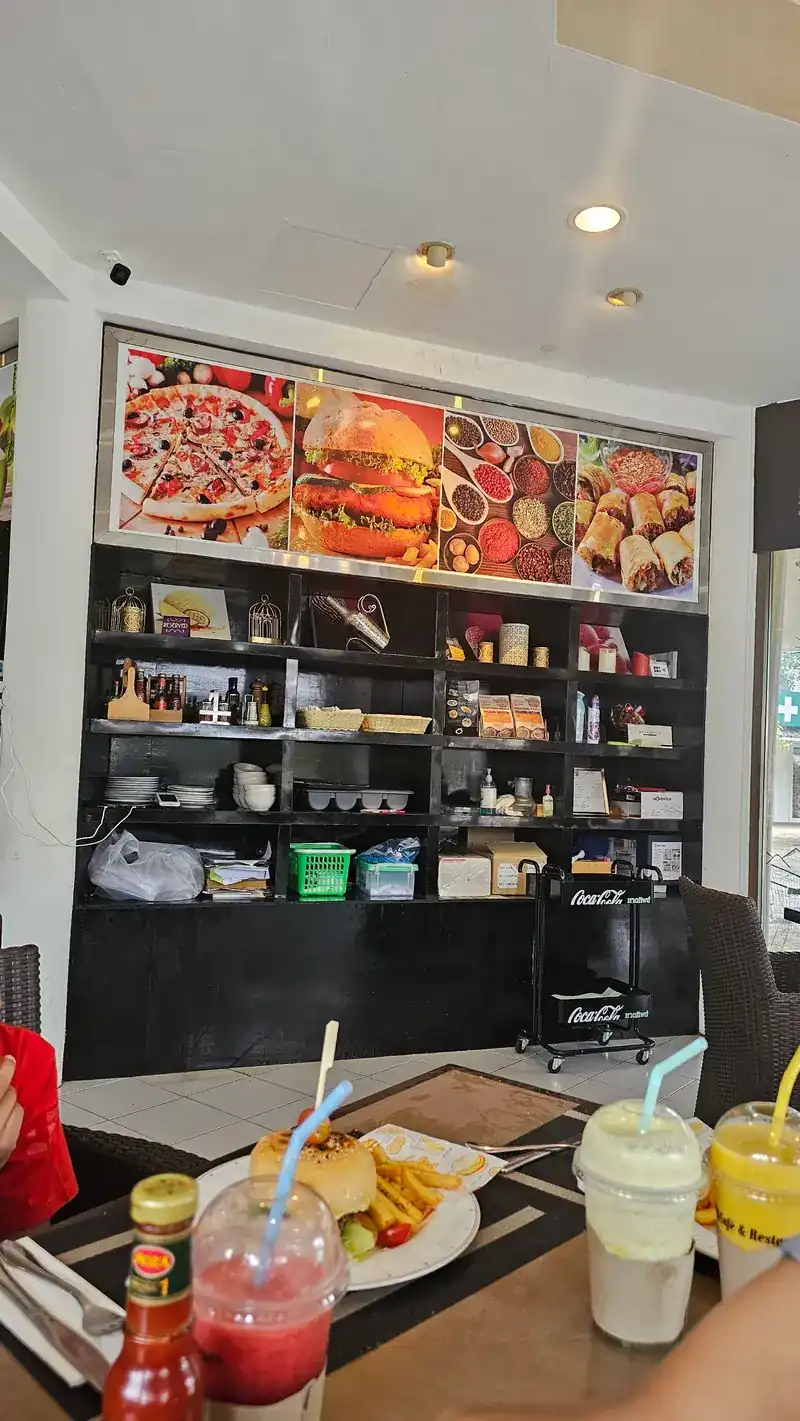 Inside the café: smoothies and a burger on the table, shelves and food pictures on the wall behind