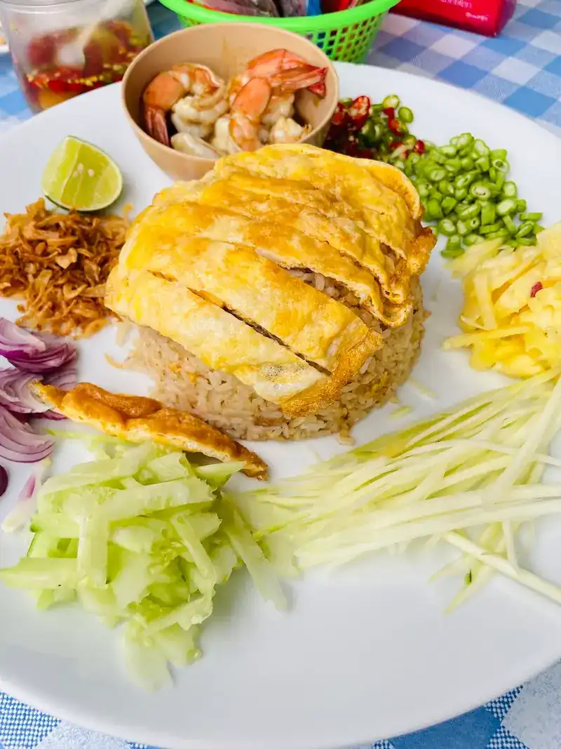 Rice topped with sliced omelette, with prawns, green mango and fresh vegetables on the side