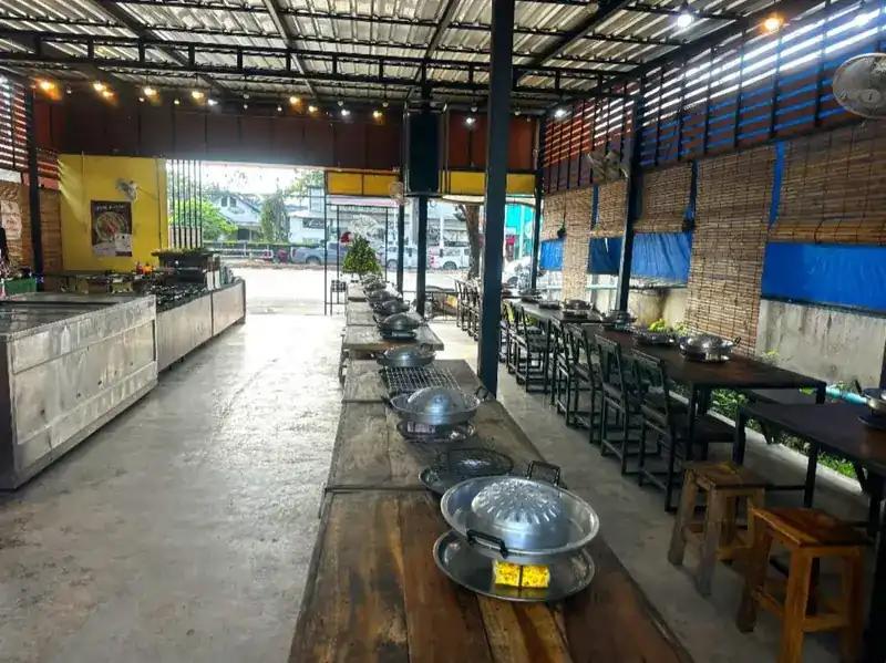 The open hall: long wooden tables set with pans, and the buffet counters on the left