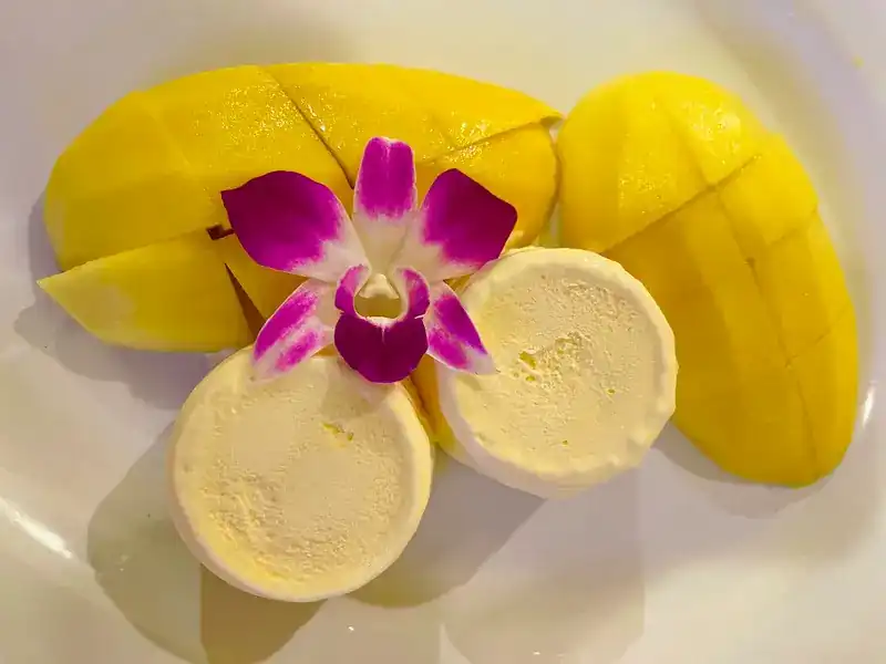 Sliced mango with two rounds of ice cream and an orchid