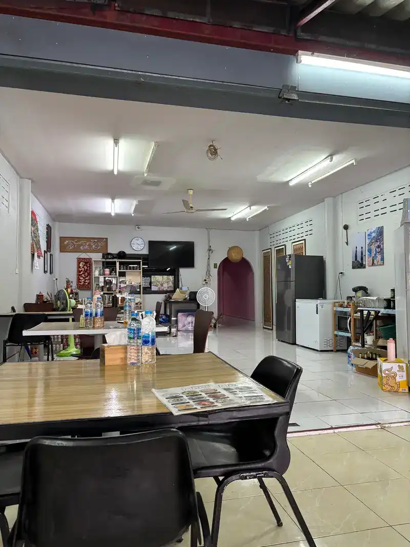 The long dining room inside, with tables, fans and a wall clock