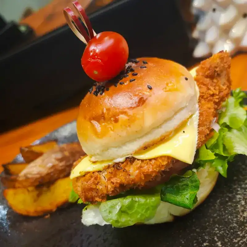 A crumbed cutlet burger with cheese, lettuce and potato wedges